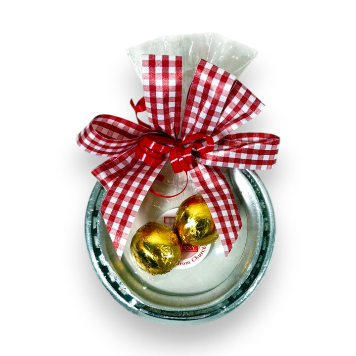 Authentic Churchill Downs horseshoe topped with two foil-wrapped Gourmet Bourbon Balls, tied with a gingham bow on a white background.