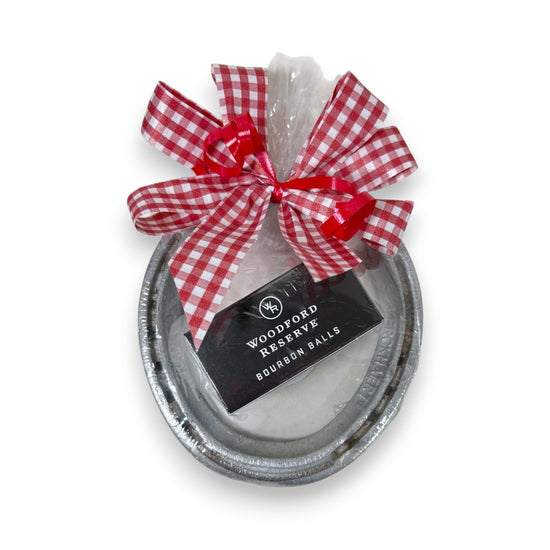 Authentic Churchill Downs horseshoe paired with a two-piece box of Woodford Reserve bourbon balls, tied with a gingham ribbon on a white background.