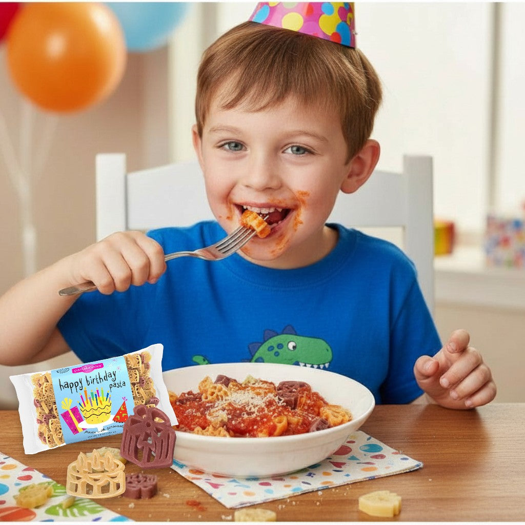 Child eating pasta with a birthday cake package and decorations in the background
