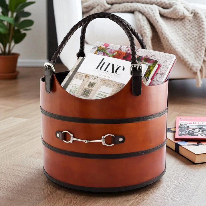 Brown leather basket with magazines on a wooden floor