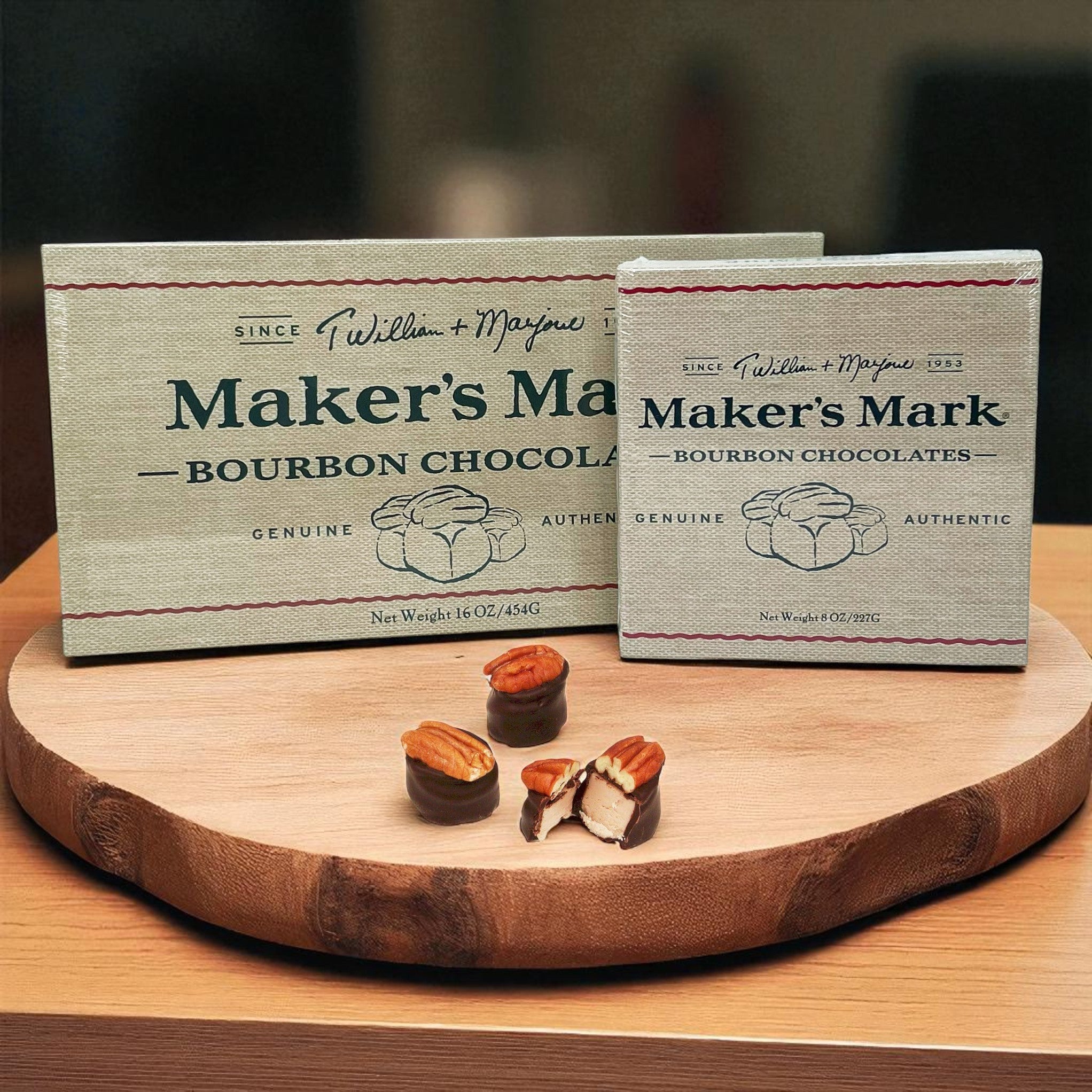 Two boxes of Maker's Mark Bourbon Chocolates on a wooden board with a blurred background.