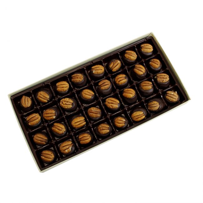 Box of chocolates with pecans on a white background