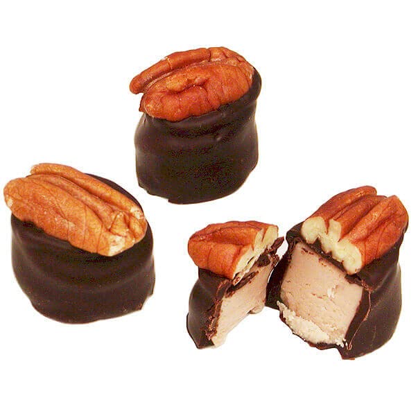 Chocolate-covered pecans with one cut open to reveal the filling on a white background