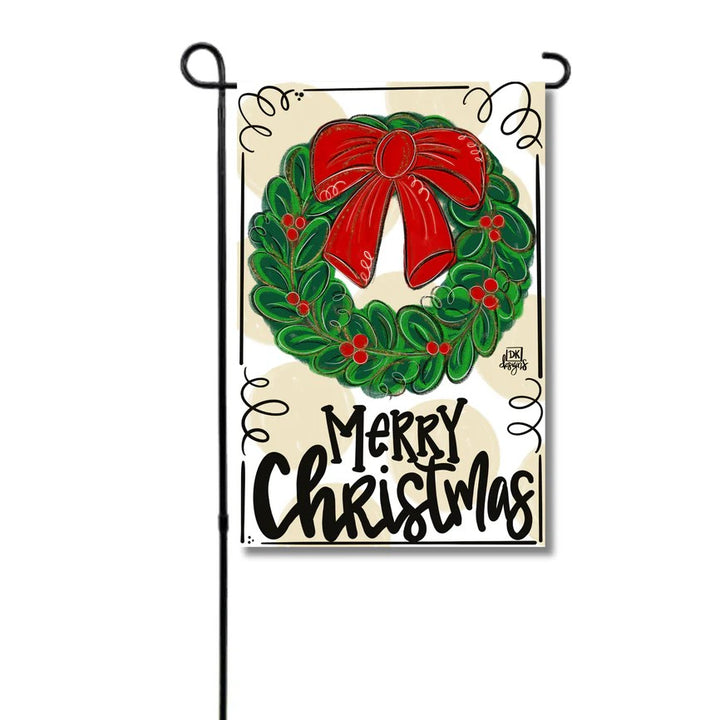 A "Merry Christmas" garden flag featuring a wreath with a red bow, hanging on a black stand.
