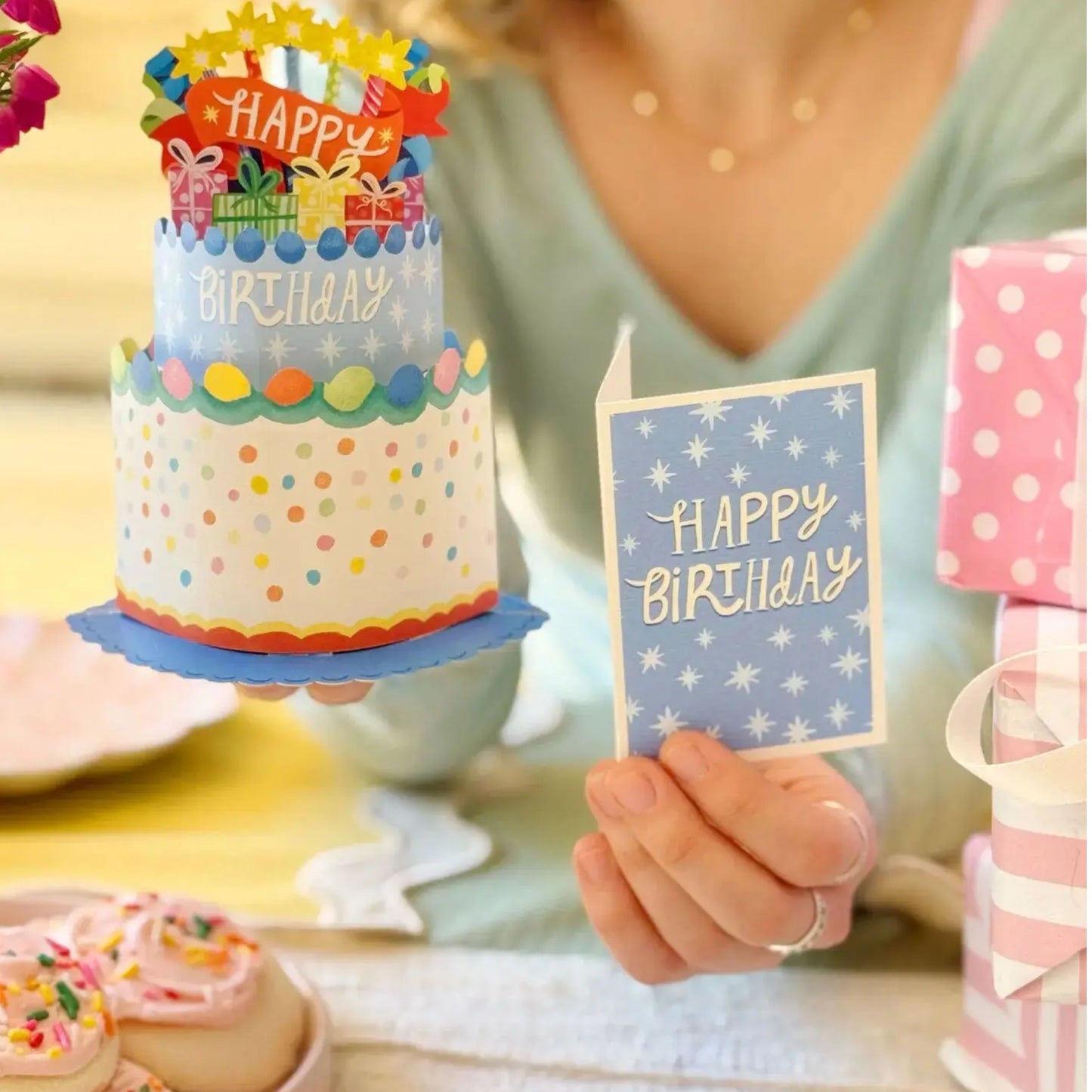 Person holding a small birthday cake with colorful decorations and a 'Happy Birthday' card.