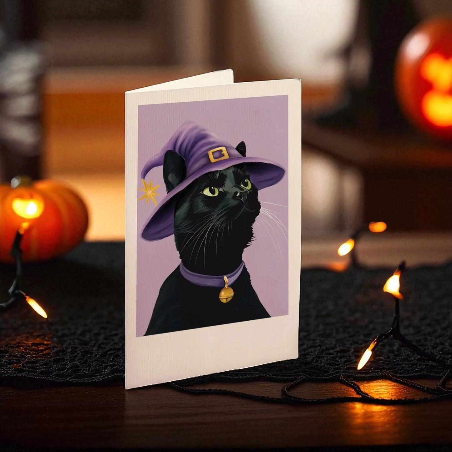Halloween-themed card with a black cat wearing a purple witch hat on a dark background with pumpkins and lights.