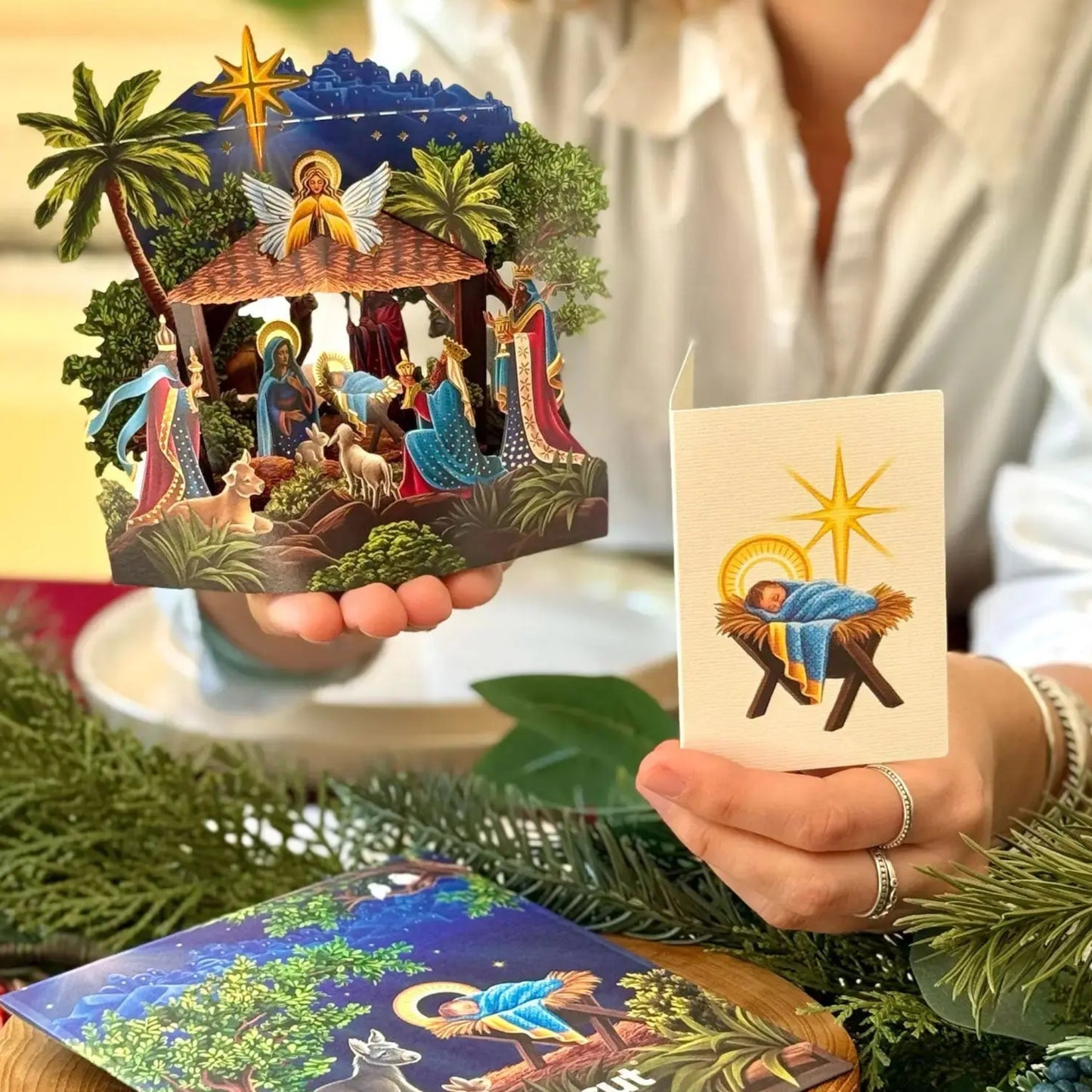 Person holding a nativity scene pop-up card with a traditional design.