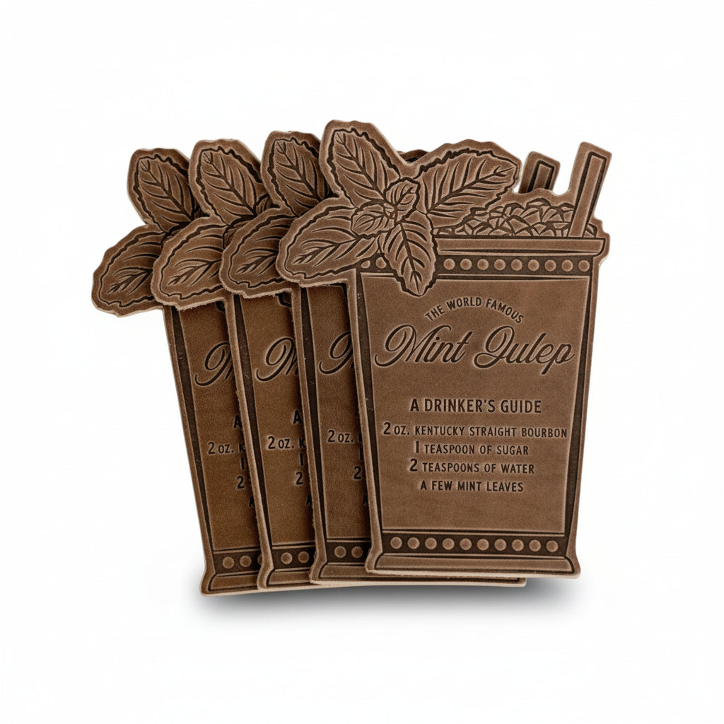 A set of four brown Horween leather coasters, each featuring a debossed Mint Julep recipe, arranged on a white background.