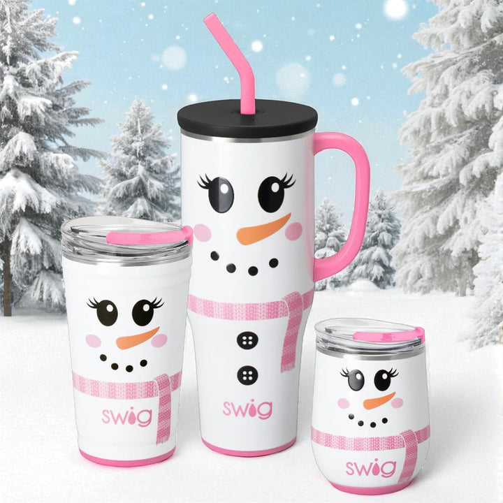 Three Ms. Frost holiday snowman tumblers—40oz mega mug with handle and straw, 24oz party cup, and 12oz stemless wine—white with pink scarf accents, shown in a snowy evergreen backdrop.