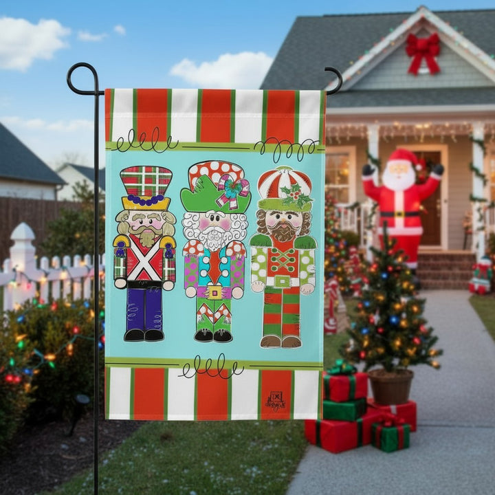 A Soldier Trio garden flag displayed in a front yard with festive decorations in the background.