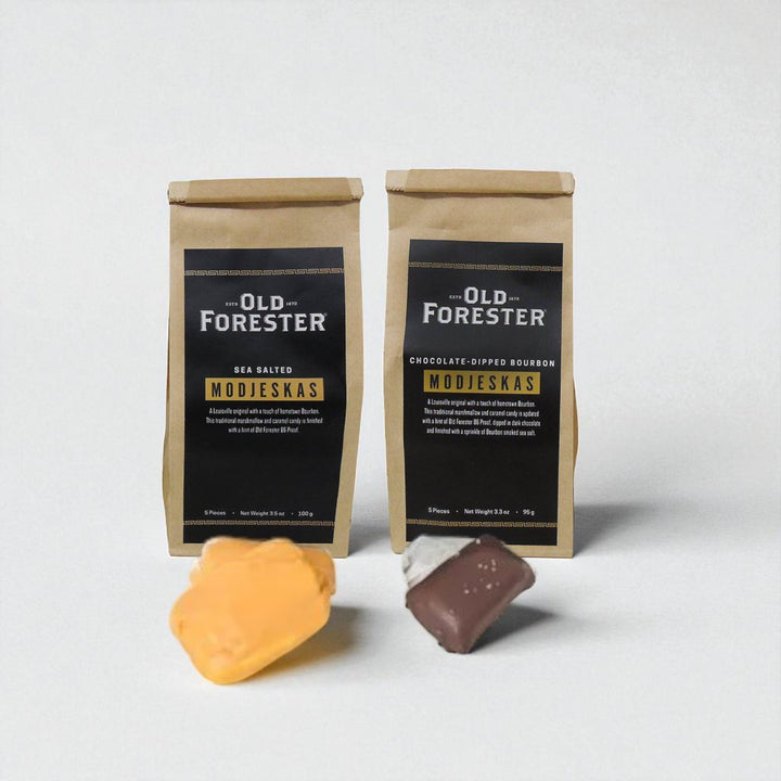 Two packages of Old Forester Modjeskas with two treats in front on a white background