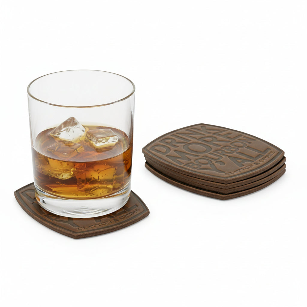 A glass of bourbon resting on a leather coaster, highlighting the rich grain and the word "Bourbon" in the design.