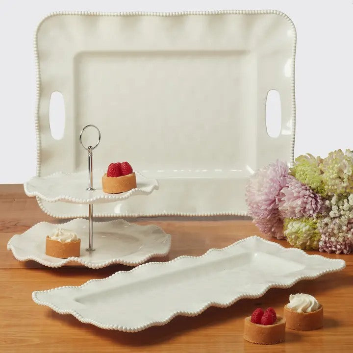 Set of white ceramic trays with scalloped edges on a wooden surface.