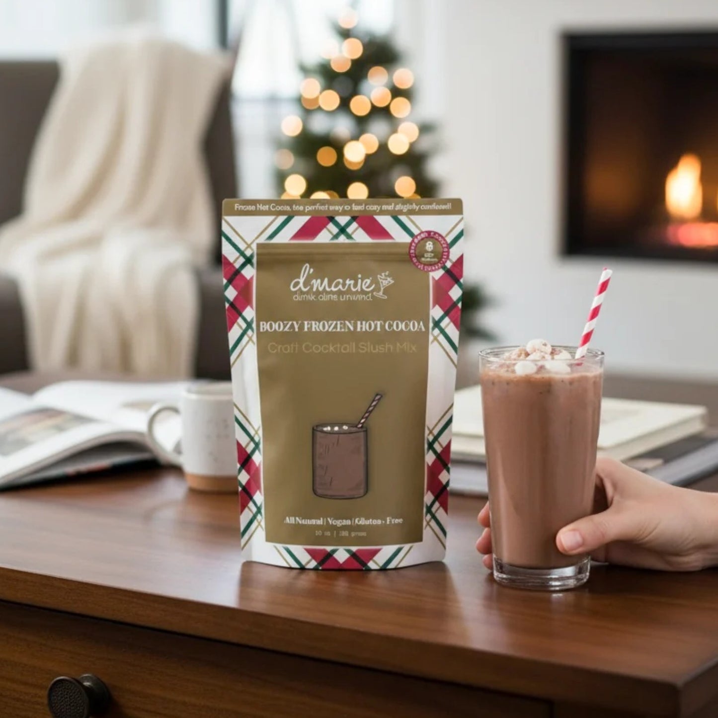 D'marie boozy frozen hot cocoa mix package with a glass of hot chocolate on a table.
