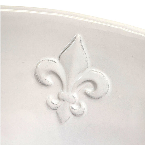 Close-up detail shot of the textured Fleur de Lis motifs on the edge of the serving bowl.