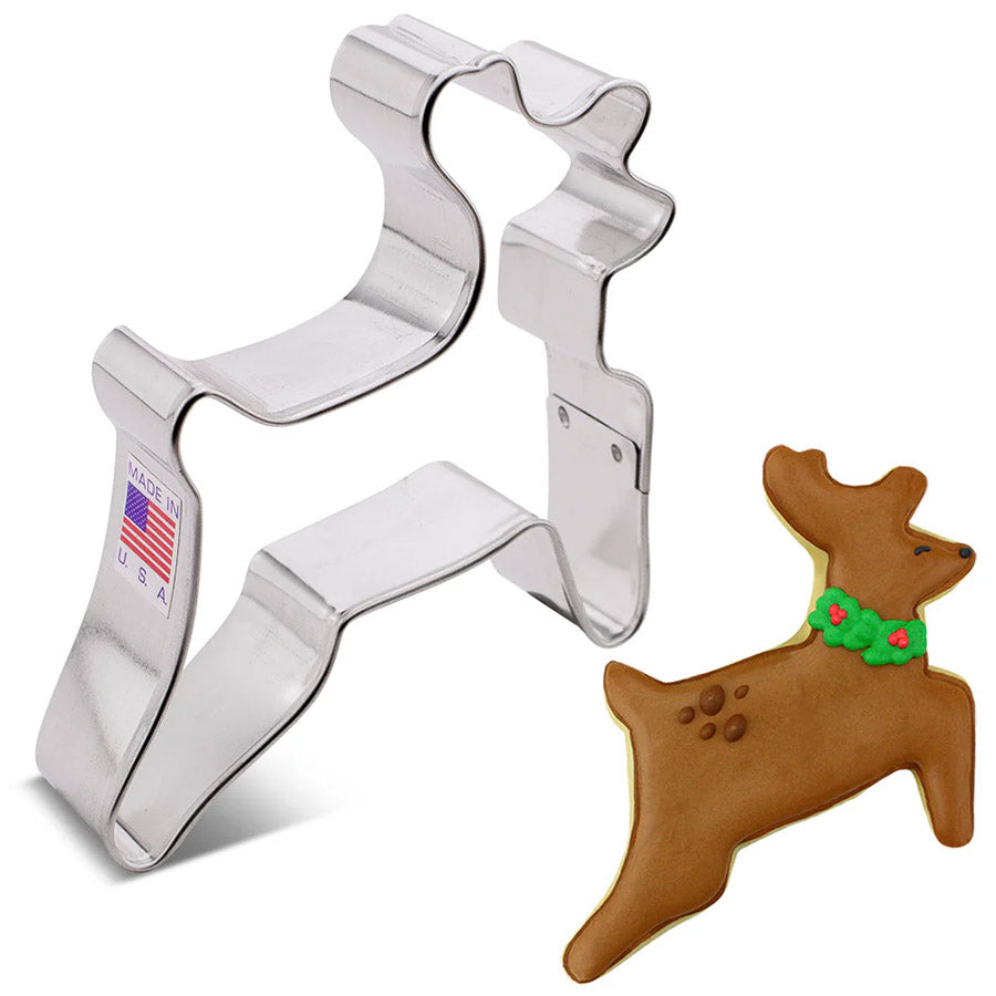 Metal reindeer cookie cutter with a gingerbread reindeer cookie on a white background