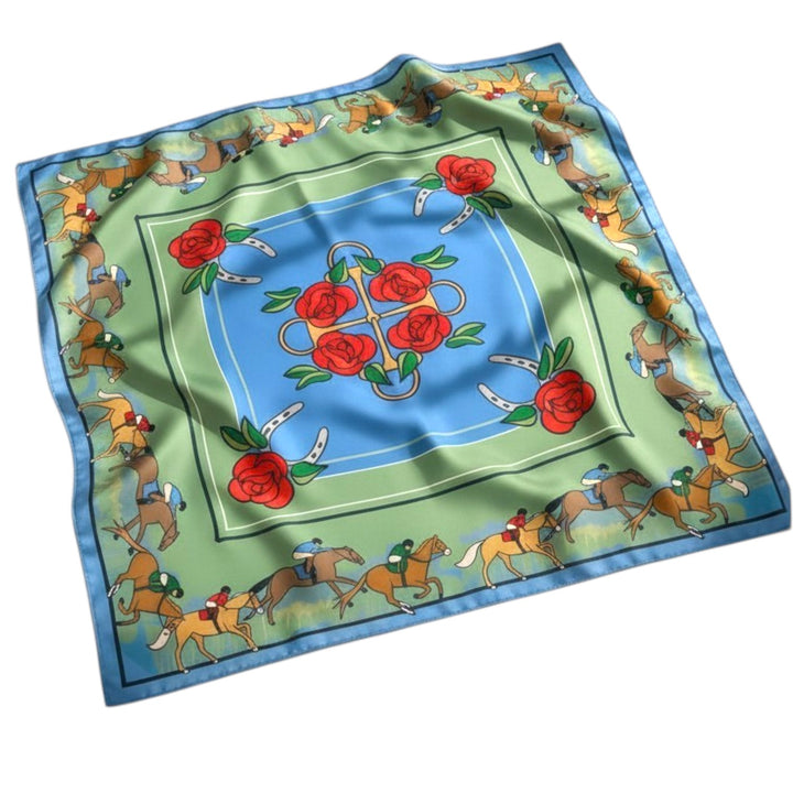 Flat lay of the Roses and Reins square silk-like scarf featuring a custom Kentucky Derby equestrian design with jockeys, horseshoes, bits, and red roses.