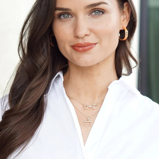 A model wearing the shiny gold Roux Horsebit Necklace, adding a touch of effortless elegance to her look.