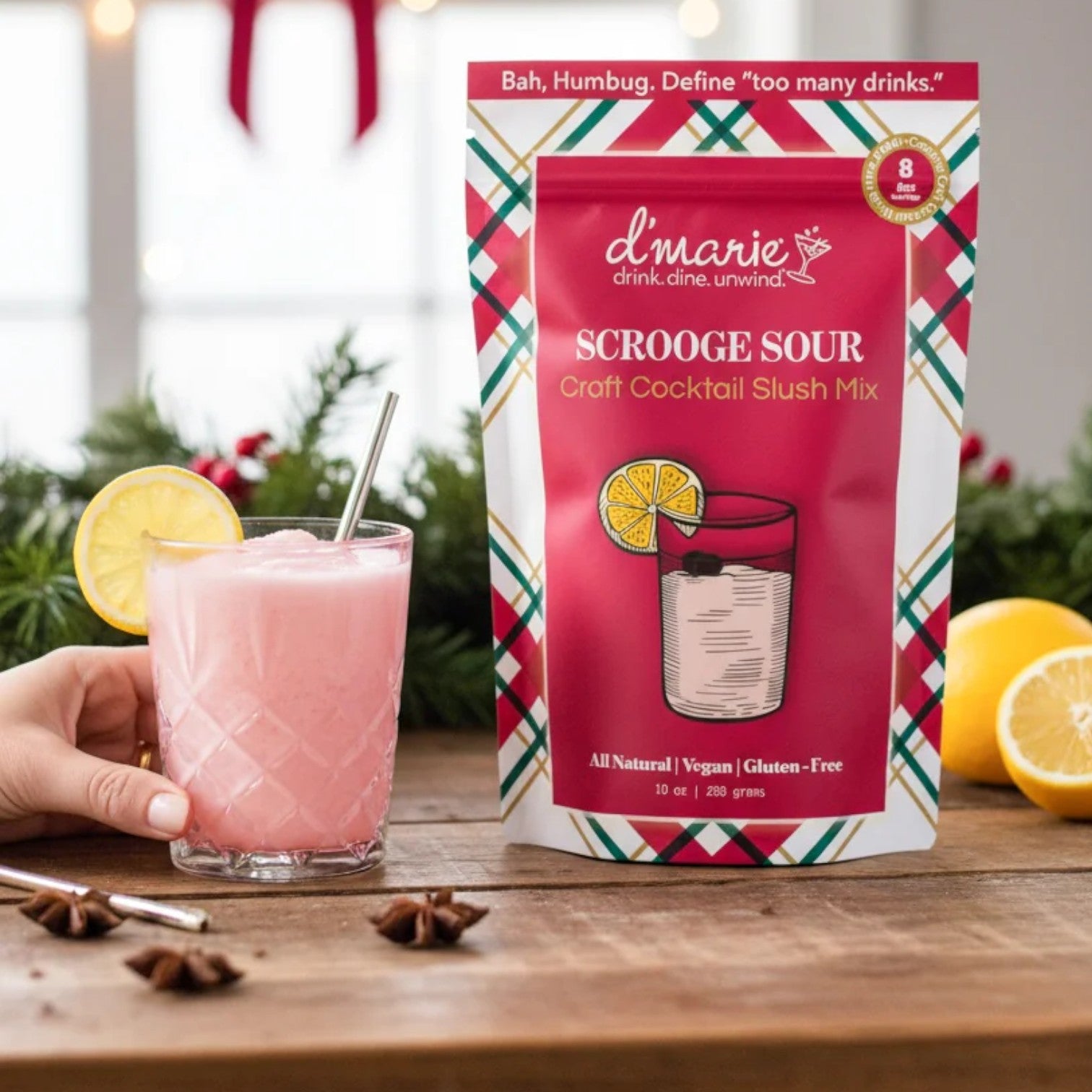 The "Scrooge Sour" slush mix pouch next to a pink cocktail in a glass.