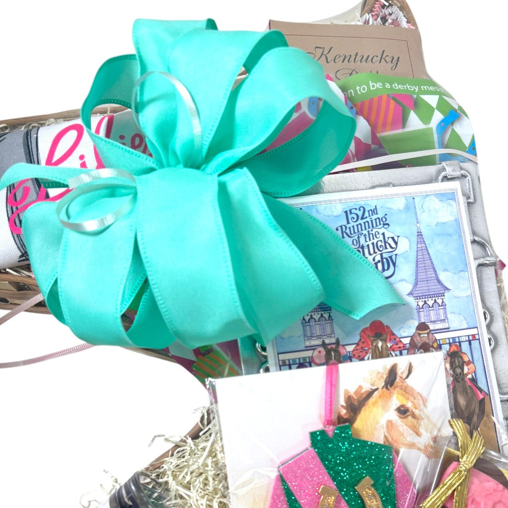 Gift basket with a large turquoise bow, Kentucky Derby-themed items, and a horse race poster.