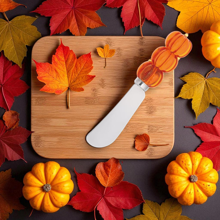 Wooden cutting board with a knife, surrounded by autumn leaves and pumpkins on a dark surface.