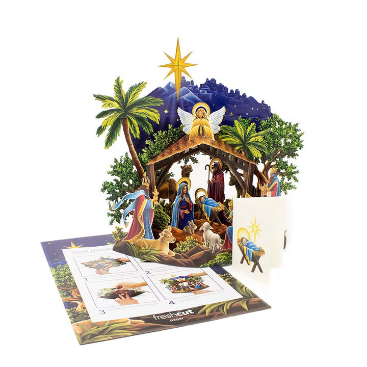 Pop-up nativity scene card with detailed illustration of a nativity scene, palm trees, and a star on a white background.
