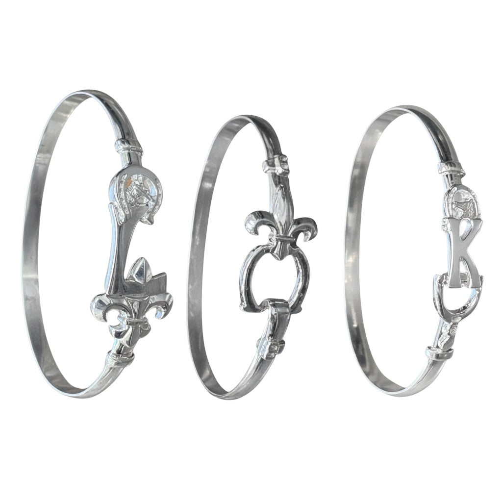 Three silver bangles with intricate designs on a white background