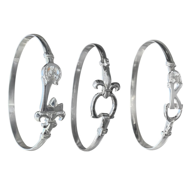 Three silver bangles with intricate designs on a white background
