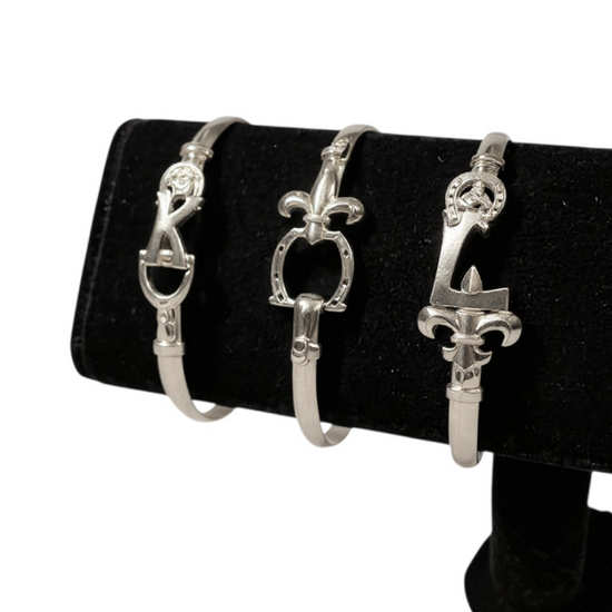 Three silver bracelet ends on a black stand with a white background