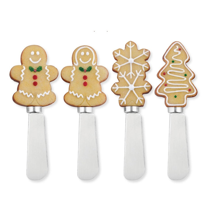 Close-up of Christmas cheese spreaders with gingerbread, tree, and snowflake handles.