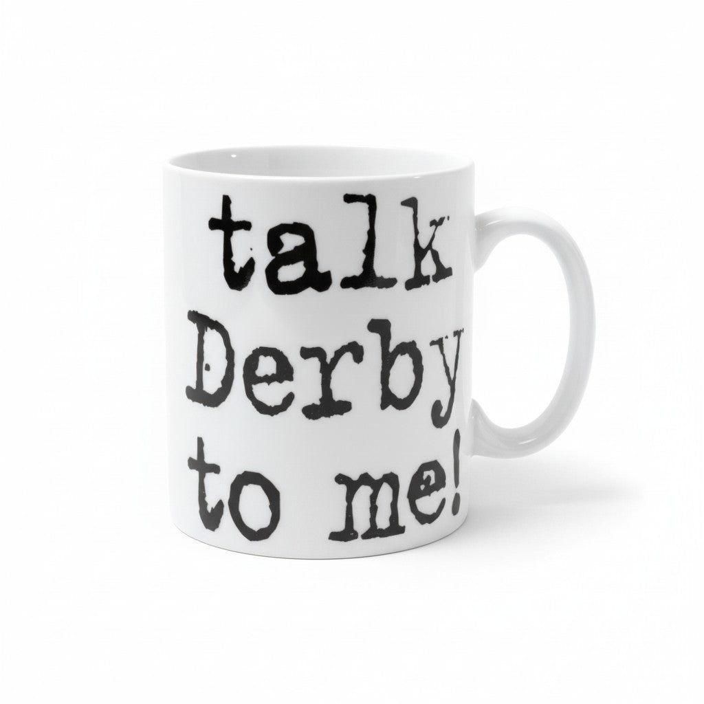 A white ceramic coffee mug featuring the playful text Talk Derby to Me printed on the front