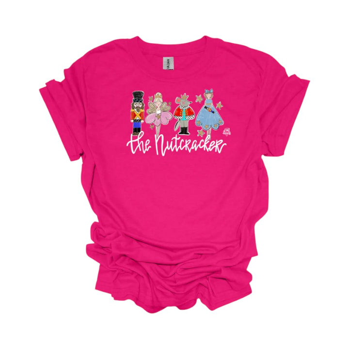 A fuchsia pink t-shirt with a graphic of Nutcracker ballet characters laid flat on a white background.