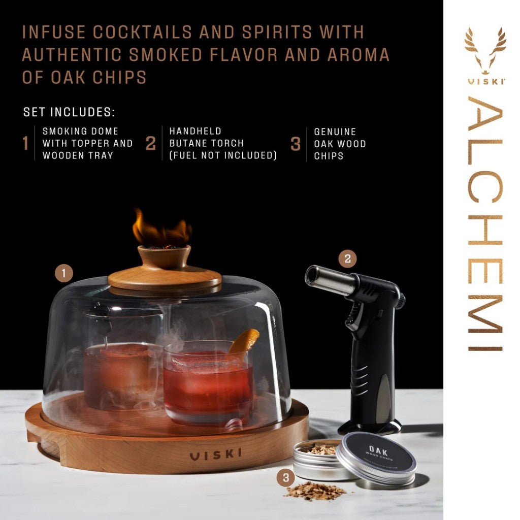 A stunning lifestyle shot of the Viski Alchemi Cocktail Smoking Dome infusing two cocktails with rich oak smoke, placed next to a black handheld butane torch.