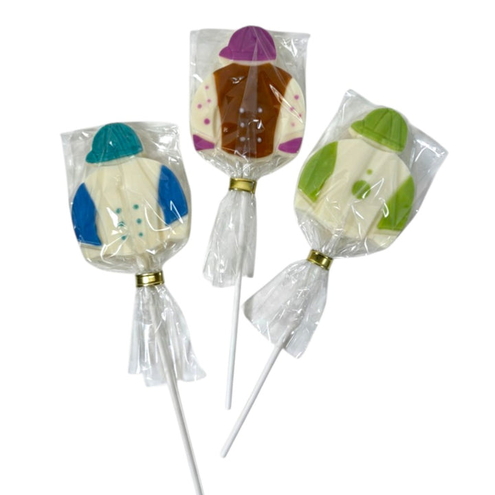 Three individually wrapped white chocolate lollipops shaped like colorful jockey silks and caps, secured with gold ties on a white background.