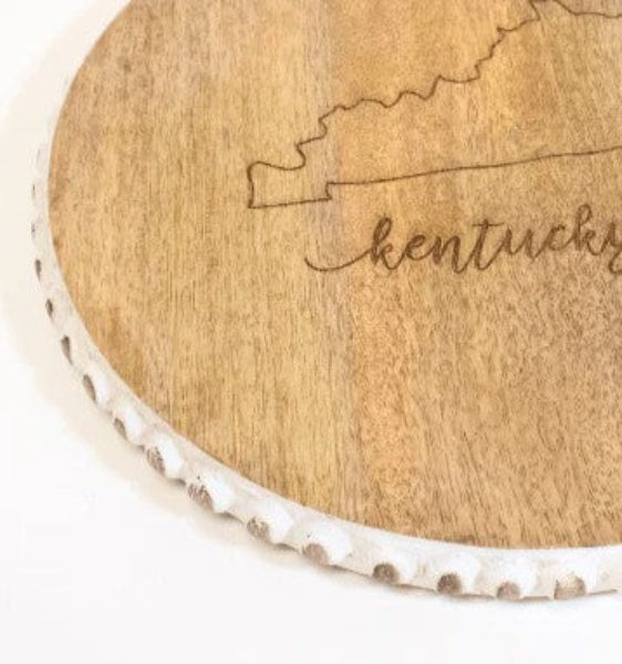 A close-up view of the white, scalloped and beaded edge of the decorative serving board.