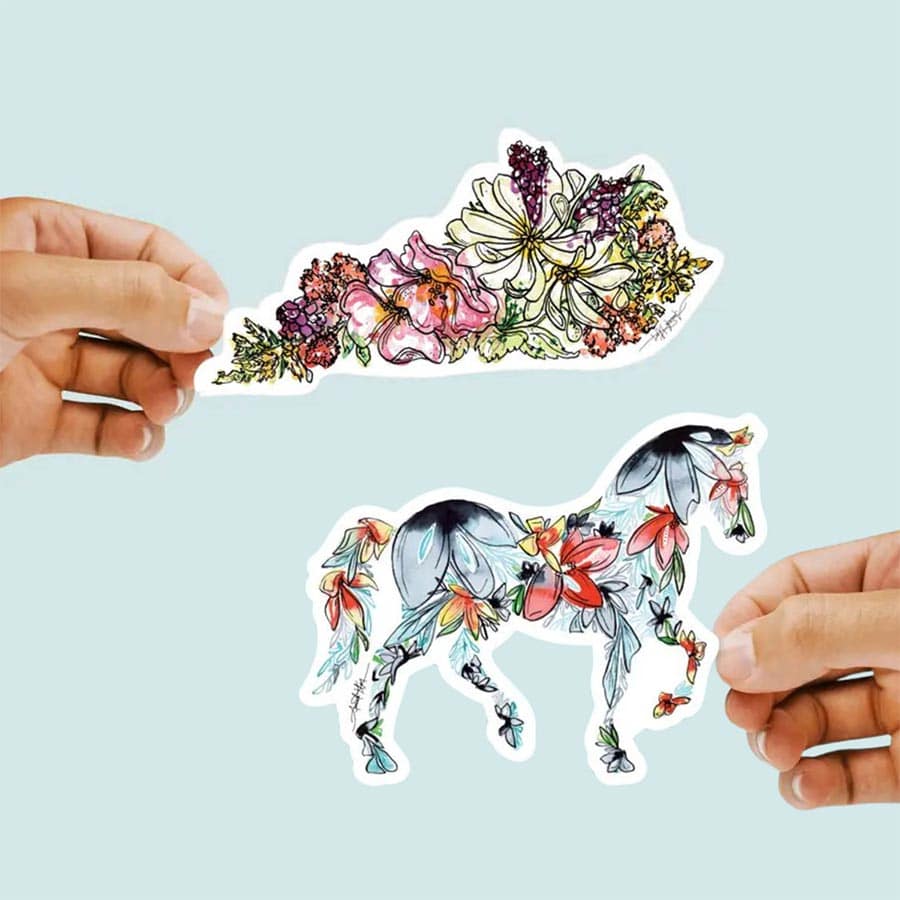 Colorful floral horse sticker held by hands against a light blue background