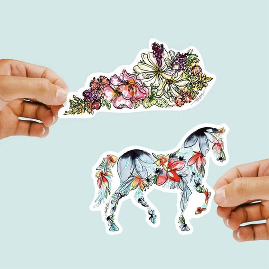 Colorful floral horse sticker held by hands against a light blue background