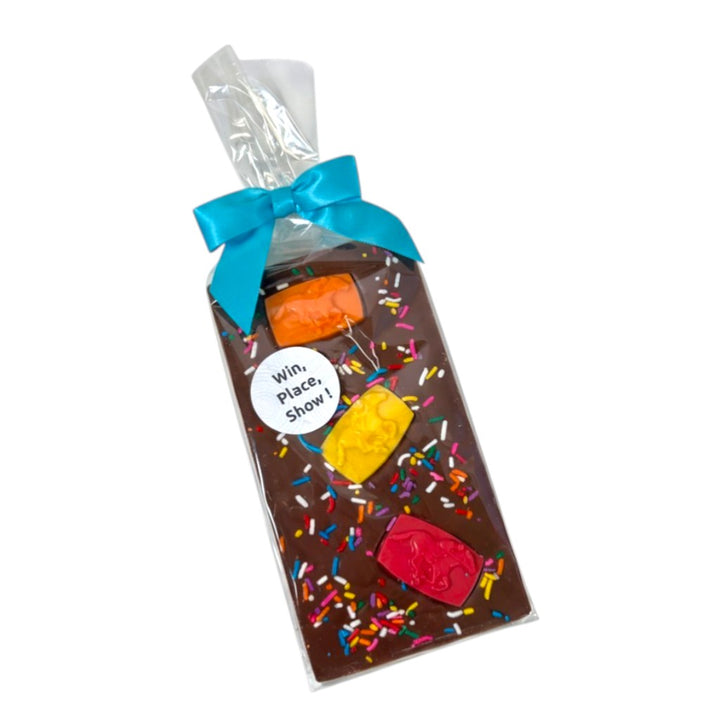 A 5.9oz milk chocolate candy bar covered in colorful sprinkles with three molded horse candies, packaged in a clear bag with a blue ribbon.
