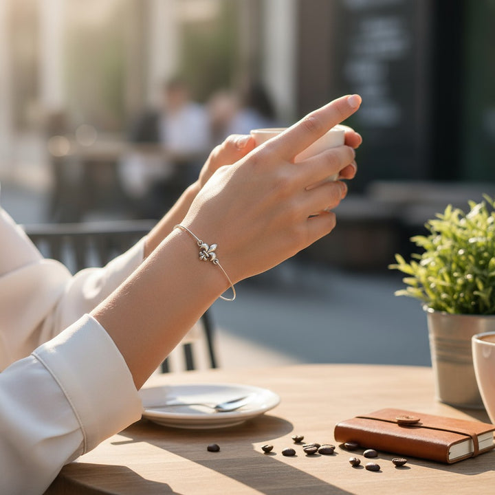 A lifestyle photo of a woman wearing the fleur de lis bracelet while holding a coffee cup.