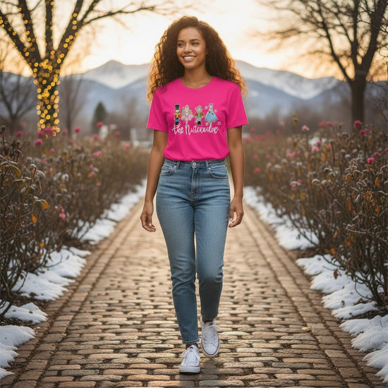 A woman smiling while wearing 'The Nutcracker' ballet t-shirt on a snowy cobblestone path.