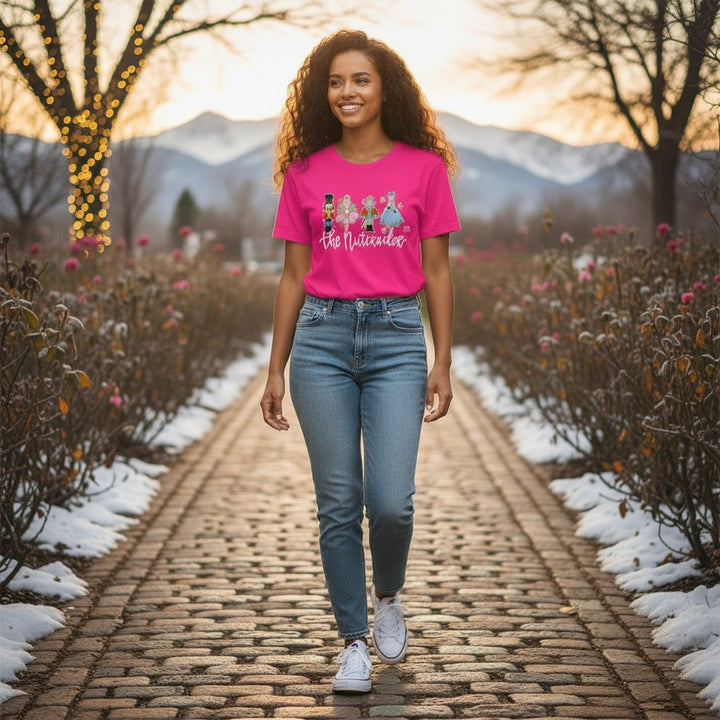 A woman smiling while wearing 'The Nutcracker' ballet t-shirt on a snowy cobblestone path.