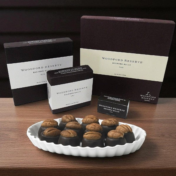 Woodford Reserve bourbon balls on a white plate with branded boxes in the background.