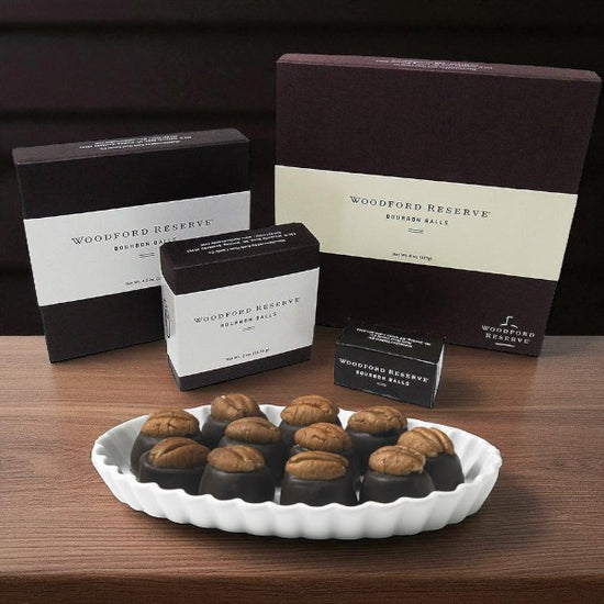 Woodford Reserve bourbon balls on a white plate with branded boxes in the background.