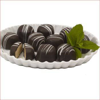 Assorted chocolate truffles on a white plate with a sprig of mint.