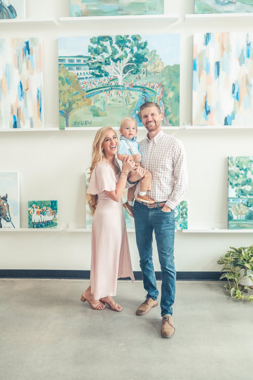 Family posing in front of a wall full of art