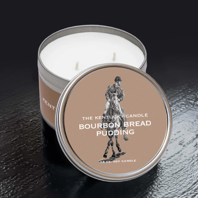 Round White Tin Candle in Bourbon Bread Pudding Scent. Sitting on black background.