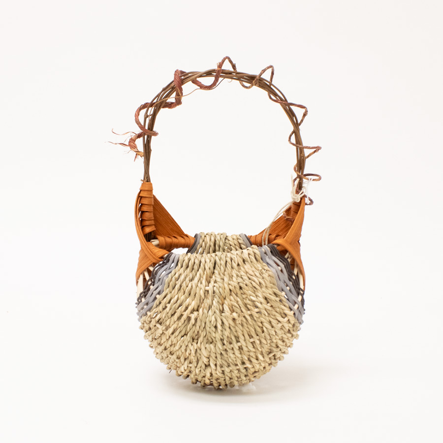 small wall hanging basket woven out of sea grass and rattan with orange, black, and grey handle accents